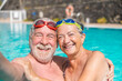 © Daniel - Couple of two happy seniors having fun and enjoying together in the swimming pool taking a selfie picture smiling and looking at the camera. Happy people enjoying summer outdoor in the water.