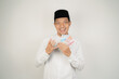 © Aria Armoko - happy asian muslim man holding money, wearing arabic costume on isolated background