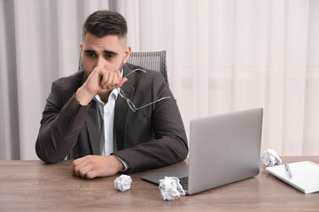 Wall Mural - Sad businessman sitting at table in office