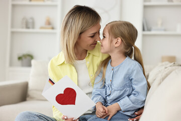 Wall Mural - Little daughter congratulating her mom with greeting card at home. Happy Mother's Day