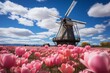A windmill stands in a field of pink tulips under a blue sky