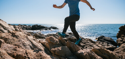 Wall Mural - Woman runner running on sunrise seaside rocky mountains