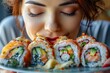 Young Woman Enjoying a Plate of Fresh Sushi Rolls with Excitement and Appetite, Close-Up Food Experience