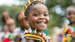 A young girl with a colorful headdress smiles directly at the camera