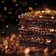 A close-up photograph of a rich Belgian chocolate cake, with multiple layers of moist cake and creamy chocolate ganache, sprinkled with gold leaf on top.