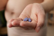 Closeup of woman hand holding pills or vitamins for pregnant females showing her bare belly standing in home interior taking care if her health during pregnancy
