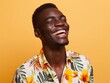 Close-up of a happy African man in a floral shirt against a vibrant orange background, embodying joy and positivity.