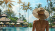 woman with a hat relaxing by the luxury pool resort