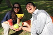 two friends out on a picnic in the garden holding healthy fresh fruits *3