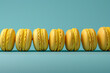 Row of yellow macaroons on a blue background. Copy space.