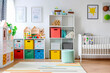 White nursery room with shelves and colourful boxes.