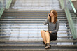 A young woman sitting on the marble staircase and talking on mobile