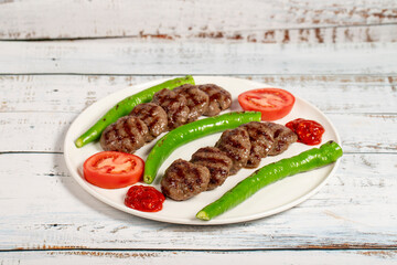 Wall Mural - Grilled meat balls. Turkish grilled meatballs with roasted peppers and tomatoes on wooden background