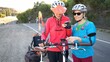 © Robert Peak - Senior and mature woman take a break while biking to look at a map on their phone for directions. Making a call.