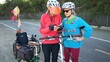 © Robert Peak - Senior and mature woman take a break while biking to look at a map on their phone for directions. Making a call.
