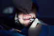 Dentist makes ultrasonic cleaning of teeth of patient using special tools.