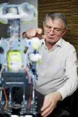 Elderly grey-haired man trials electrical design indoor.