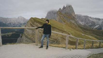 Wall Mural - Man traveler stands on the observation deck in the national park of mountain Seceda in the Dolomites. Alps mountains in autumn or winter. Beautiful alpine mountains in Italy. Seceda, one of the most
