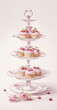 Three-tiered stand with pink frosted cupcakes and raspberries, cherries and roses.