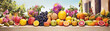 Still life of various fruits and flowers arranged on a stone table with a blurred background of a villa