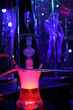 Hookah with illumination and woman stripper dances out of focus in night club