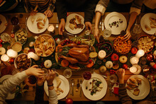 Top Down View With Anonymous Family Children Friends Gathered At Home For A Festive Christmas Dinner. Diverse People Enjoy Delicious Turkey Feast And Share Stories. Cozy Holiday Celebration