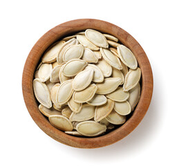 Wall Mural - Pumpkin seeds in a wooden plate on a white background. Top view