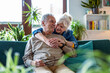 © pikselstock - Portrait of a happy senior couple sitting on sofa at home