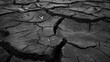 Cracked black surface of fertile soil in severe drought in a lean year, background with selective focus