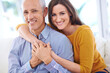 © ArcursJointTeam/peopleimages.com - Happy, couple and hug in portrait, love with unique relationship and support for trust at home. Aged man, young woman and age difference in marriage, commitment and loyalty with pride together