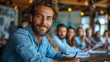 © Raptecstudio - a man with a beard is sitting at a table with a group of people