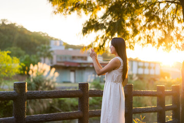 Sticker - Woman take photo on cellphone under sun flare in the countryside