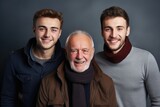 Fototapeta Kwiaty - Three generations of men posing together with happy smiles on a dark background. Generations of Men Smiling Together