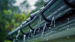 Closeup of the rain falling on the aluminum gutter on the house shingles roof, water drainage