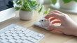 Cute white mouse sitting on a real computer mouse and a human hand ready to click on it