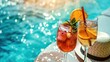 Glasses with refreshing fruit cocktail, on a table with a straw hat, next to the pool, on a summer day.