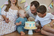 © Elena - Adorable boy making a wish as he blows out the candle on his festive cake.