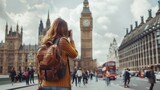 Fototapeta Big Ben - travel, tourism and people concept - happy young woman with backpack and camera photographing over london city street and big ben tower background
