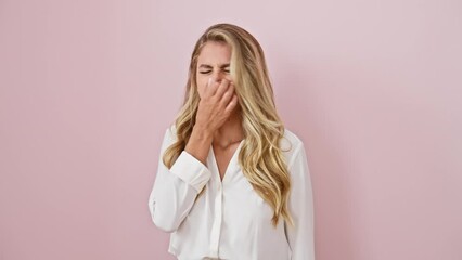 Canvas Print - Young blonde woman in shirt, standing in disgust over isolated pink background, holds breath and nose at stinky bad smell, revealing a strong stench intolerance from an unpleasant surprise.