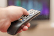 © andov - A person with a TV remote controls the remote control to switch channels to watch TV shows.