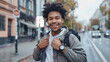 A sporty smiling young man standing on a city street checks the time after training on a smart watch on his wrist