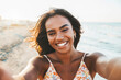 © Davide Angelini - Beautiful black young woman taking selfie picture walking on the beach - Delightful female smiling at camera outside - Summer vacation, technology and healthy lifestyle concept