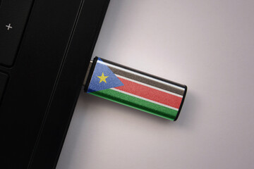 Wall Mural - usb flash drive in notebook computer with the national flag of south sudan on gray background.