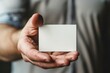 © romanets_v - A close-up of a man's hand presenting a blank white business card, with a focus on the card itself, implying a business introduction or opportunity