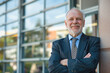 © romanets_v - A cheerful, confident mature businessman in a suit and tie standing outside a building, which could be indicative of success or leadership