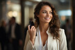 © vefimov - Woman is smiling and holding cell phone. She is wearing white jacket and she is in busy area