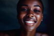 Smiling African woman looks at camera closeup. Shot of dark-skinned model with happy expression on face in dark-lit premise. Lady shows toothy smile