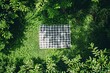 A neatly placed checkered blanket awaits a leisurely picnic in a verdant glade, promising a day of relaxation under the trees.