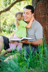 Wall Mural - happy father with a child reading a book on the nature of the Bible