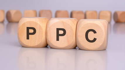 Sticker - the image depicts three wooden blocks with the letters 'PPC' in focus, reflecting on the table surface. in the background, there is a row of wooden blocks, blurred and out of focus